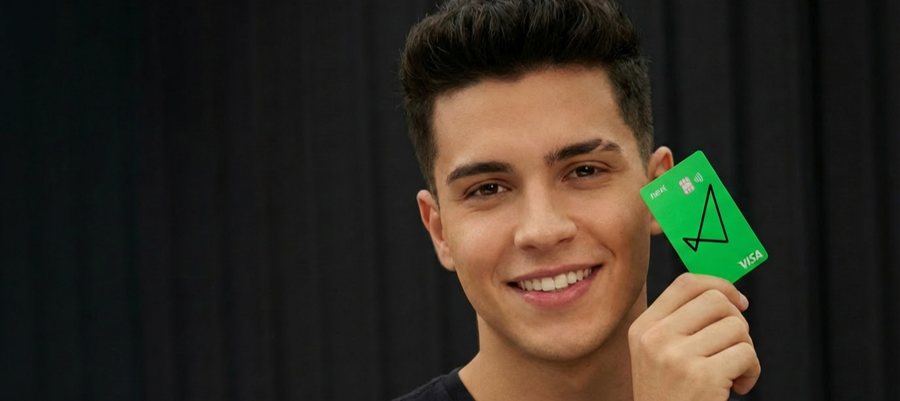 Fotografia da entrada do prédio next mostrando o térreo, com o logo do banco em primeiro plano.